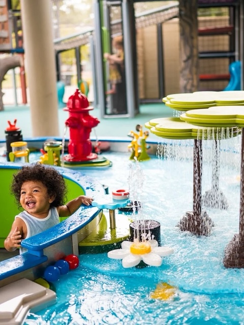 Toddler giggles and plays at water table